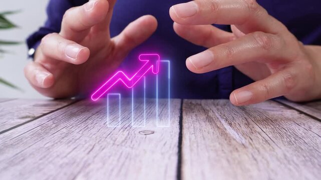 Upward trend in results. Close-up of a pair of hands on a table, protecting a virtual bar graph icon with an upward-pointing arrow.