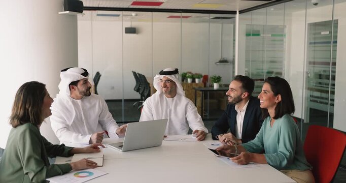 Arabic and European business partners talking and laughing on business meeting, discussing partnership, collaboration, brainstorming on creative ideas for international project