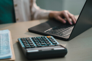 Close up of calculator on desk with person typing on laptop, representing financial accounting, business analysis, budgeting, tax calculation and modern office workflow with digital finance management