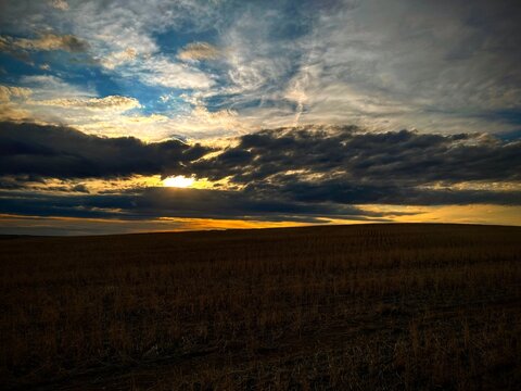 A glowing cloudscape cloaks an empty Montana field at sunset