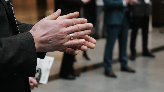 Close up of business audience clapping hands during conference or seminar in corporate event environment with blurred background.