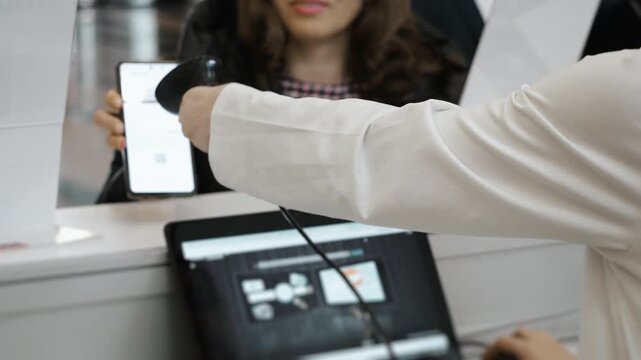Close up of attendee QR code scanning at conference registration desk using barcode scanner connected to laptop system during event check in.