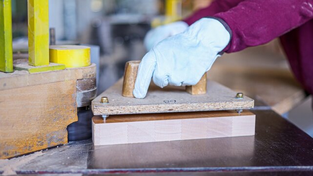 Carpenter cutting wood plank using spindler machine in workshop