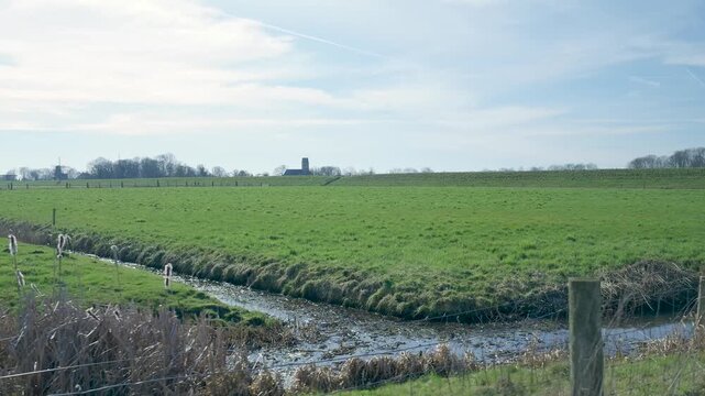 Dutch polder landscape with a green meadow and windmill