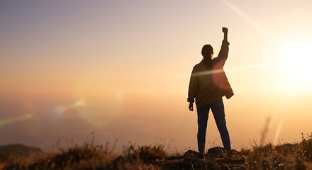 Fototapeta premium Silhouette of a woman raising fist in success on top of the mountain at sunset.