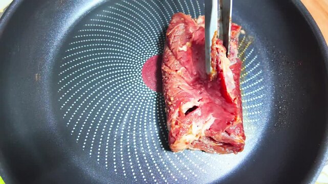 Cooking meat in a frying pan over a hot plate