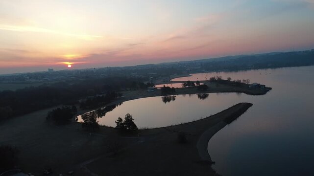Beautiful sunrise captured by drone over &Scaron;těrkovna Hluč&iacute;n near Hluč&iacute;n. The aerial view shows a calm lake, colorful clouds, and spring landscape of the Czech Republic, creating a peaceful morning view
