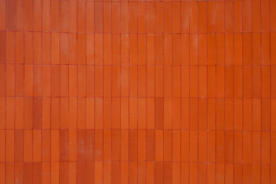 Modern architectural background featuring vertical orange ceramic wall cladding.