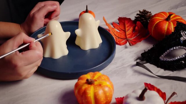 Cutting out Halloween jelly ghosts among festive fall decor with pumpkins and leaves