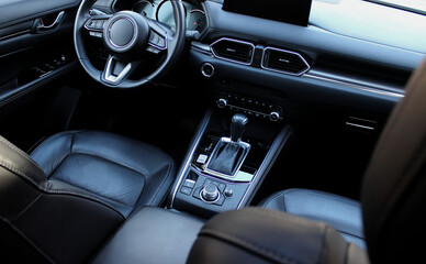 Fototapeta premium Classic design of the front part of the car interior finished with aluminum and black leather. Modern Car Front Seats and Controls On A Center Console
