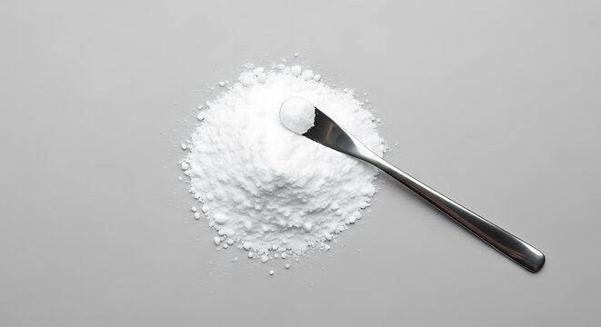 A small metal spatula resting on a neat pile of white powdered substance on a grey background. allantoin