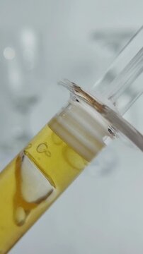 Yellow gel serum resembling honey texture in syringe-like packaging. Facial cleanser product, vertical composition, close up view isolated on white background for skincare presentation.