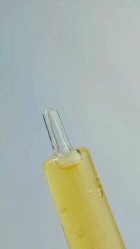 Close up of hand opening serum cap, golden yellow beauty skincare product with precise movement on clean background.
