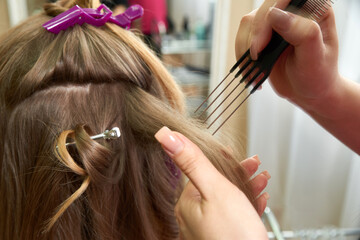 Fototapeta premium Hairdresser styling hair of a client in beauty salon