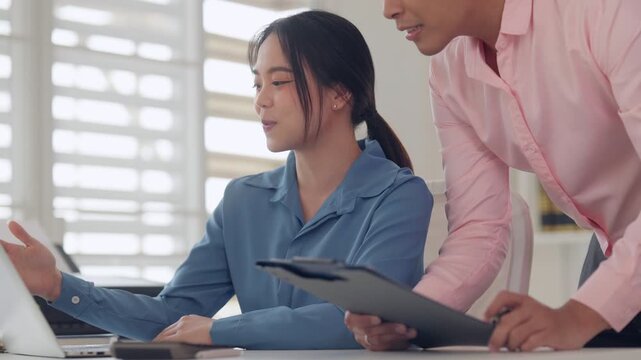 Asian young adult professional woman working laptop computer completing business tasks modern bright office environment for productivity achieving goals