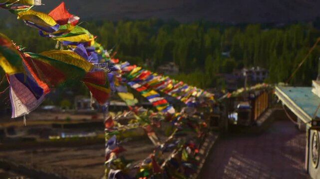 Buddhist Prayer Flags Waving in Wind with Himalayan Mountains and Stupas on Sunny Day