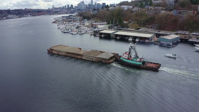 Drone Aerial Footage of Tugboat Pushing Gravel Barge Through Seattle Waterway &ndash; Industrial Marine Vessel, Working Boat, Waterfront, Cargo Transport, Urban Harbor Scene