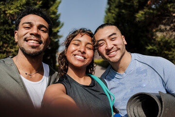 Fototapeta premium Diverse young friends smiling taking outdoor fitness selfie