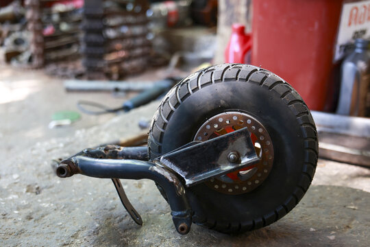 Custom vehicle wheel and tire assembly with brake part of mechanical project. Focused work to build something unique and handmade inside garage, showing gritty craftsmanship