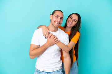 Naklejka premium Young caucasian couple isolated on blue background laughing and hugging