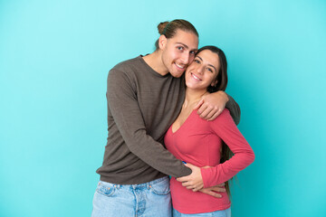 Naklejka premium Young caucasian couple isolated on blue background hugging