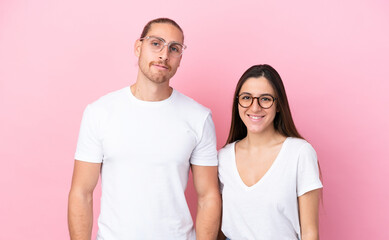 Fototapeta premium Young caucasian couple isolated on pink background With glasses with happy expression