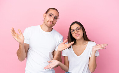 Fototapeta premium Young caucasian couple isolated on pink background With glasses and having doubts