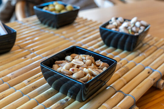 Peanuts, olives and pistachios in black bowls as an appetizer at a beach club in Spain