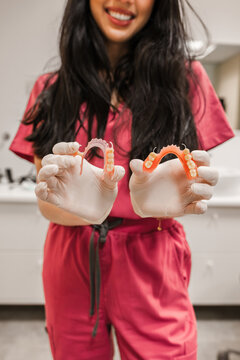 Dental professional in scrubs holding flexible removable partial dentures, offering solutions for missing teeth and oral care