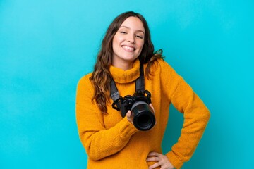 Young photographer woman isolated on blue background posing with arms at hip and smiling