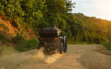 Fototapeta premium A man engages in extreme ATV riding on mountains in the evening