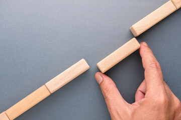 Hand placing wooden block to bridge a gap, symbolizing problem solving, connection, teamwork, closing distance and creating solutions in business or strategy © patpitchaya