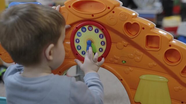 Focused little boy exploring an interactive clock in indoor playground