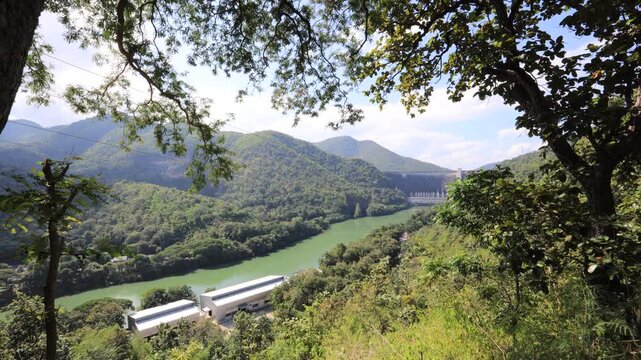 The video background features a natural aerial view of the Bhumibol Dam in Tak province, Thailand, which effectively stores water and sustains agricultural crops.