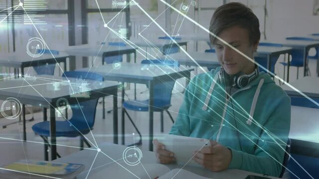 Teen male student tapping tablet in classroom, causing data overlay moving showing graphs for study