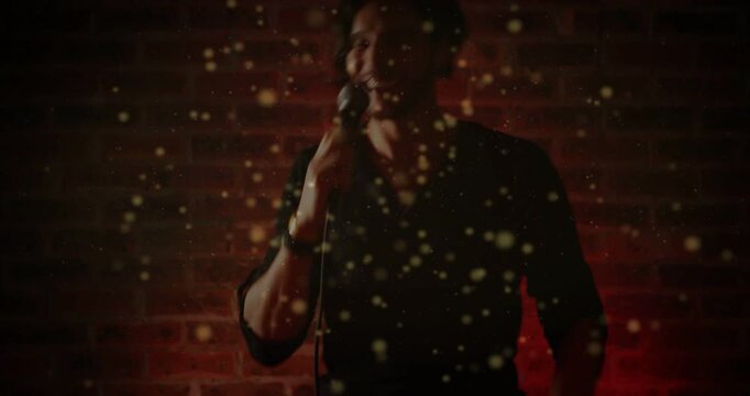 Male singer lifting mic, leaning and singing for music promo, golden flecks crossing foreground