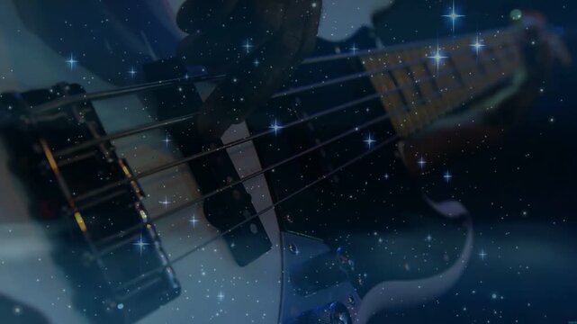 Vertical video: Bassist plucking strings in music studio, causing star flares across neck for mood