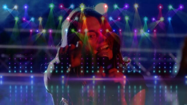 Central singer moving as camera pushes, raising mic, engaging concert crowd amid pulsing LED beams