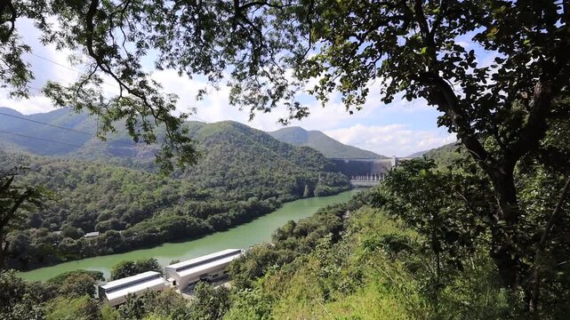 The video background features a natural aerial view of the Bhumibol Dam in Tak province, Thailand, which effectively stores water and sustains agricultural crops.