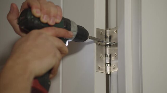 Installation of door hinges. Screwing the screw with a screwdriver