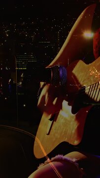 Vertical video: musician bringing mic to guitar, playing live, camera zooming in, sparkling on fret