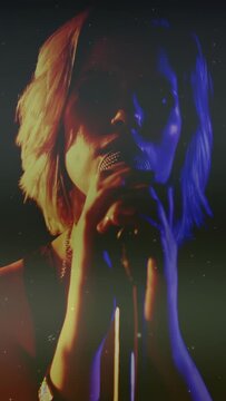 Vertical video: Cam pulling back, singer gripping mic, singing for music take under grainy lighting