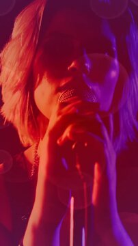 Camera starting tight on bracelet, music performer reaching mic singing while lights revealing face