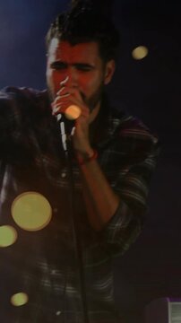 Cam zooming hand lead singer moving onstage holding mic singing engaging music fans kit keys bokeh