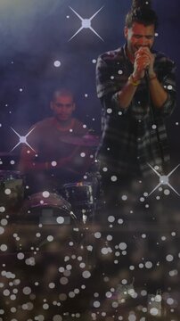 Vertical video: Singer gripping mic, leaning in, singing live, bokeh over stage, drums keeping beat