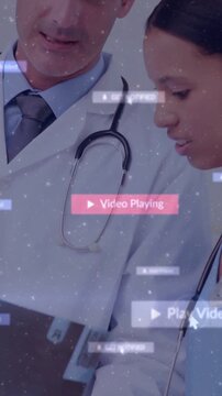 Vertical video: Doctor pointing tablet trainee leaning showing floating play UI for medical review