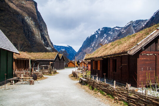 Blick durch historisches Wikingerdorf mit Holzh&auml;usern und dramatischer Berglandschaft im Hintergrund in Norwegen