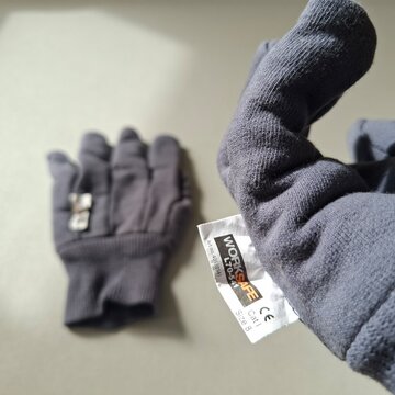 Work glows. Gray Winter Glove Standing Upright on Surface