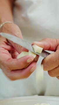 A womans hands cut provola cheese into pieces for Emilian lasagna