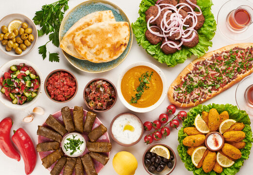 Turkish cuisine flat lay with pide, kofte, lentil soup, mezze, dolma, salads, olives, yogurt dip and flatbread on table colorful traditional assortment